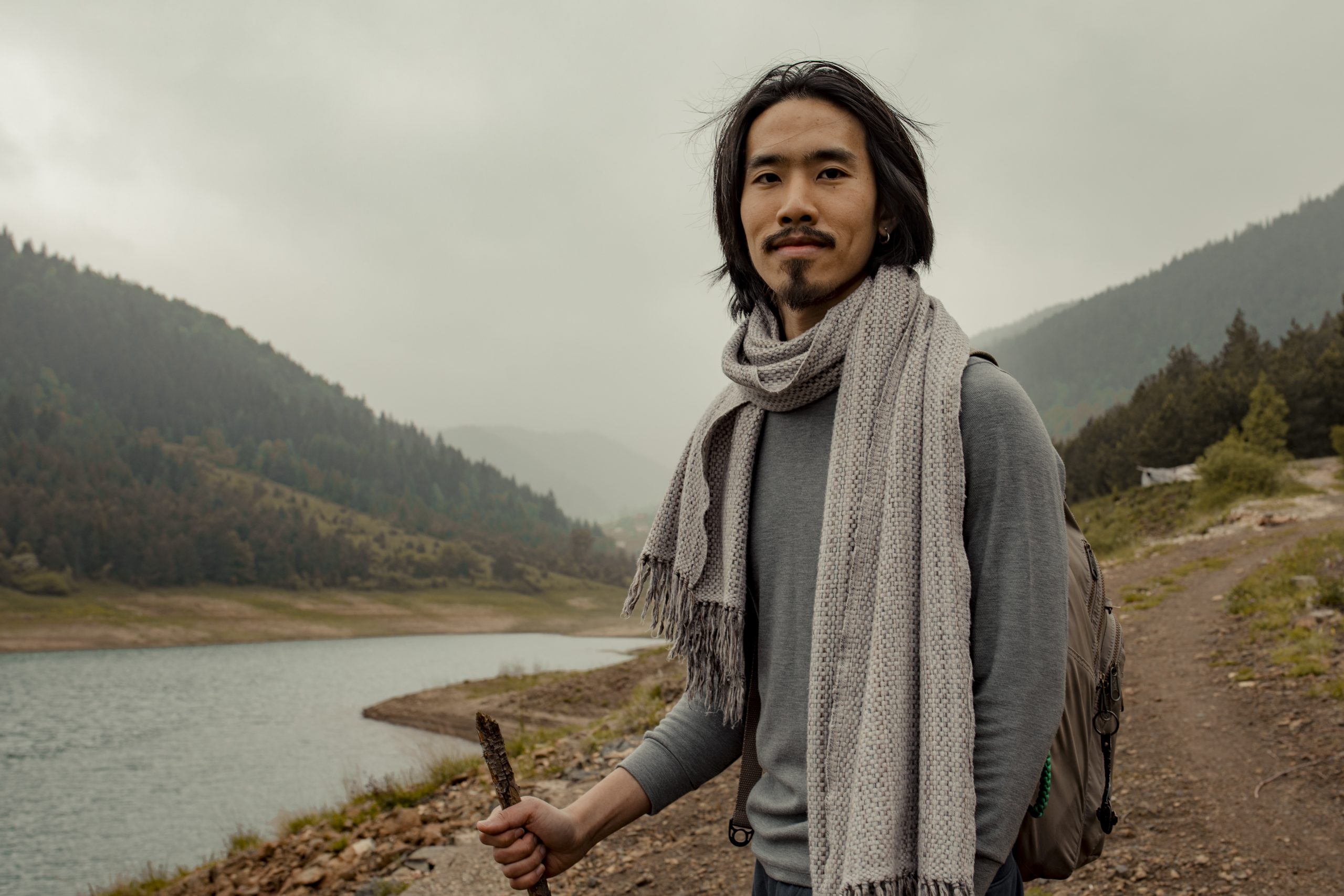Bryan Chan standing beside a misty mountain lake while hiking